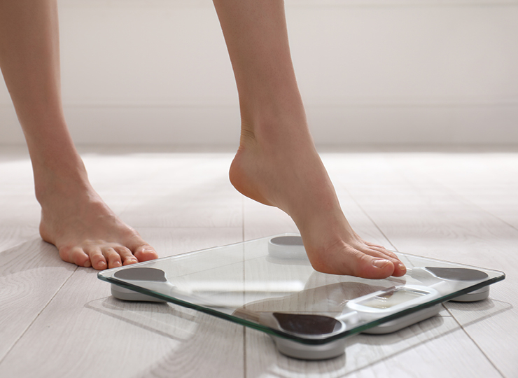 person checking their weight on a weighing scale