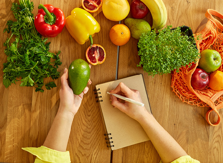 Vegetables laid out on a table, someone writing in a diary