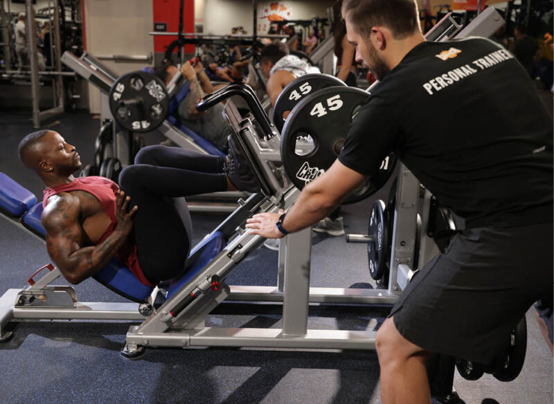 personal trainer with client on leg press machine